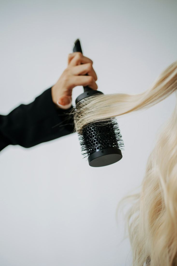 Bright blonde hair being blow-dried with a round brush