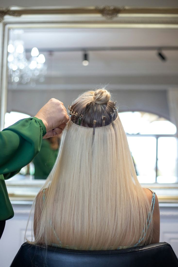 Stylist fitting long blonde hair extensions