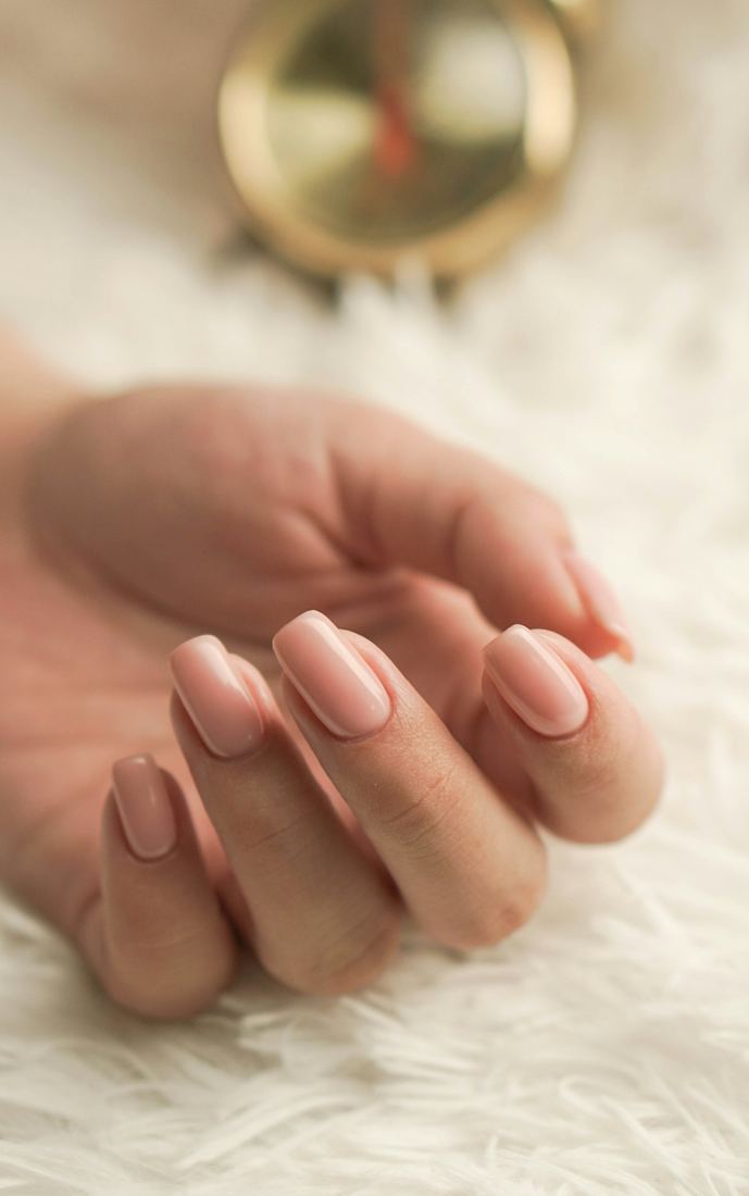 Hand with soft pink manicured nails